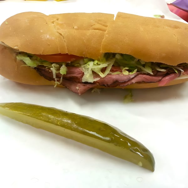 Ned's Krazy Sub with roast beef, lettuce, and tomato, served with a pickle spear.