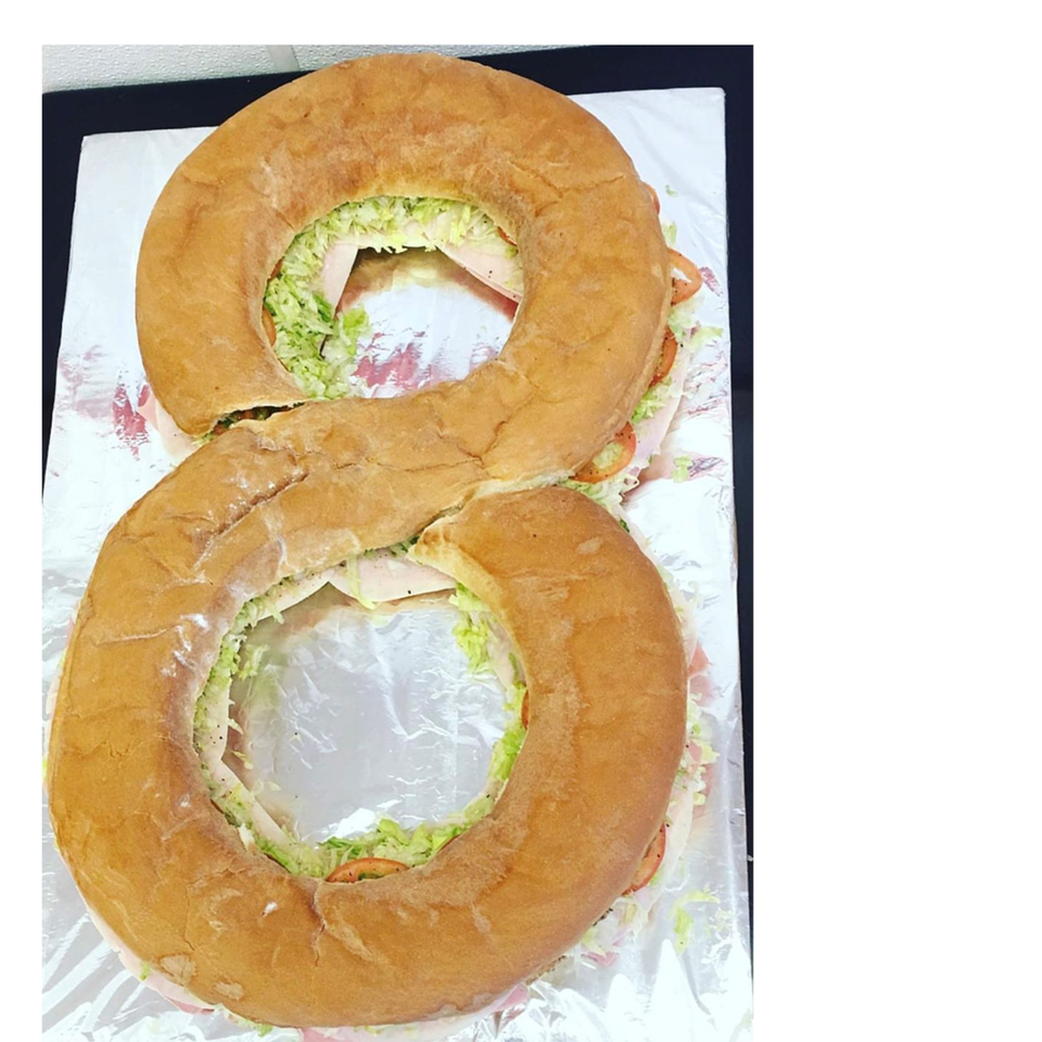 A large sub sandwich shaped like the number eight, filled with lettuce, tomatoes, and deli meat.
